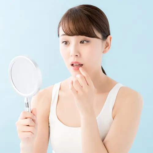 鏡で歯の色を確かめる女性